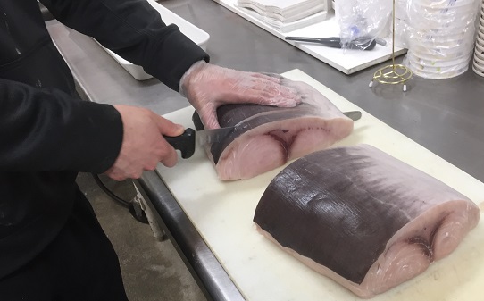 Color Photo of Employee cutting a Large Piece of Swordfish